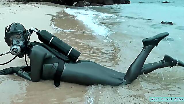 Rubber diving in latex catsuit and beach posing